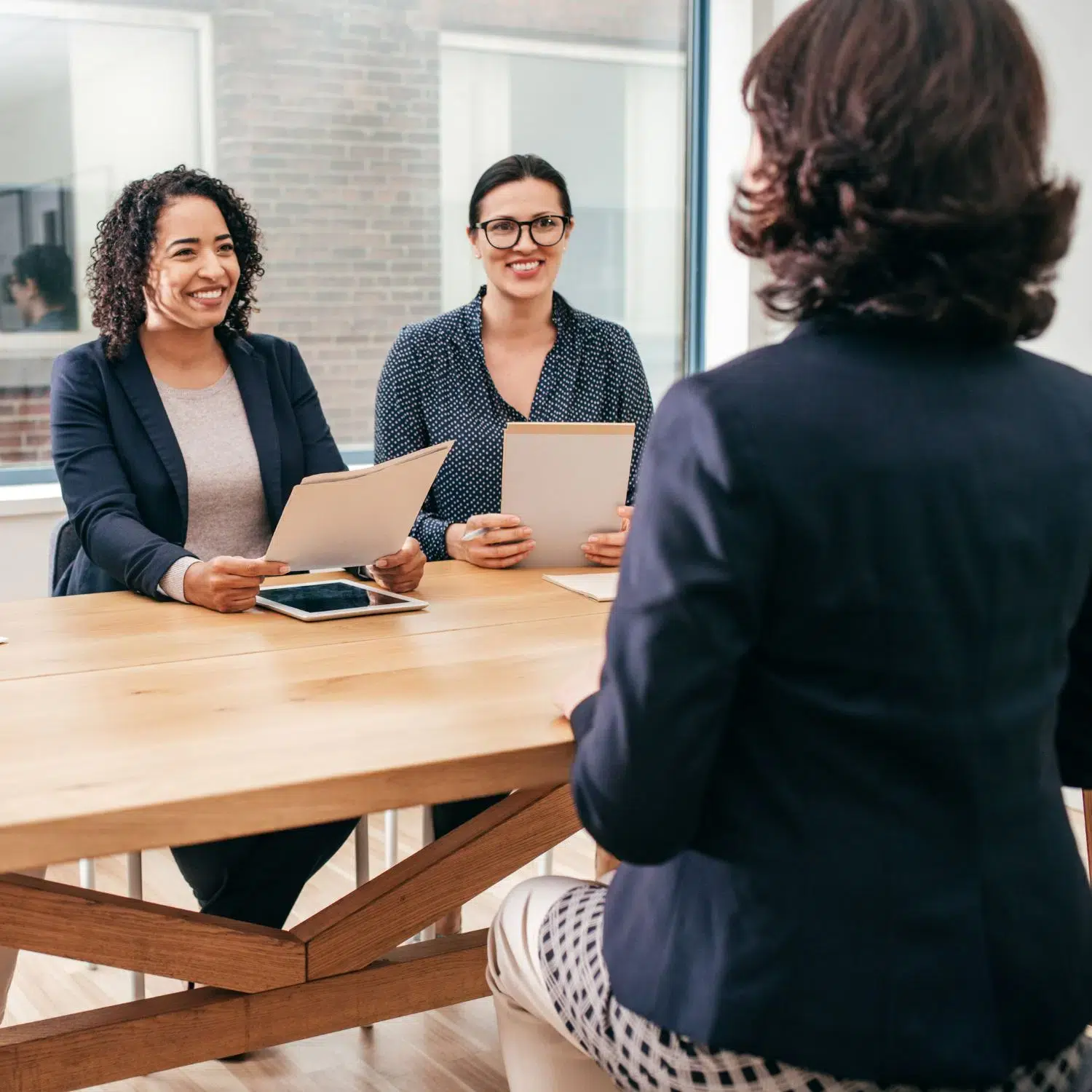 3 women sat at a desk having a meeting